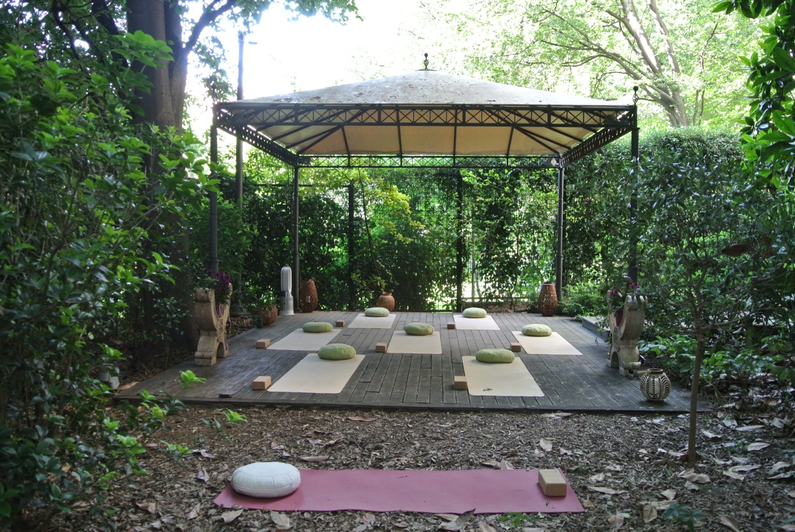 An empty garden pavilion set with yoga mats and cushions before guests arrive