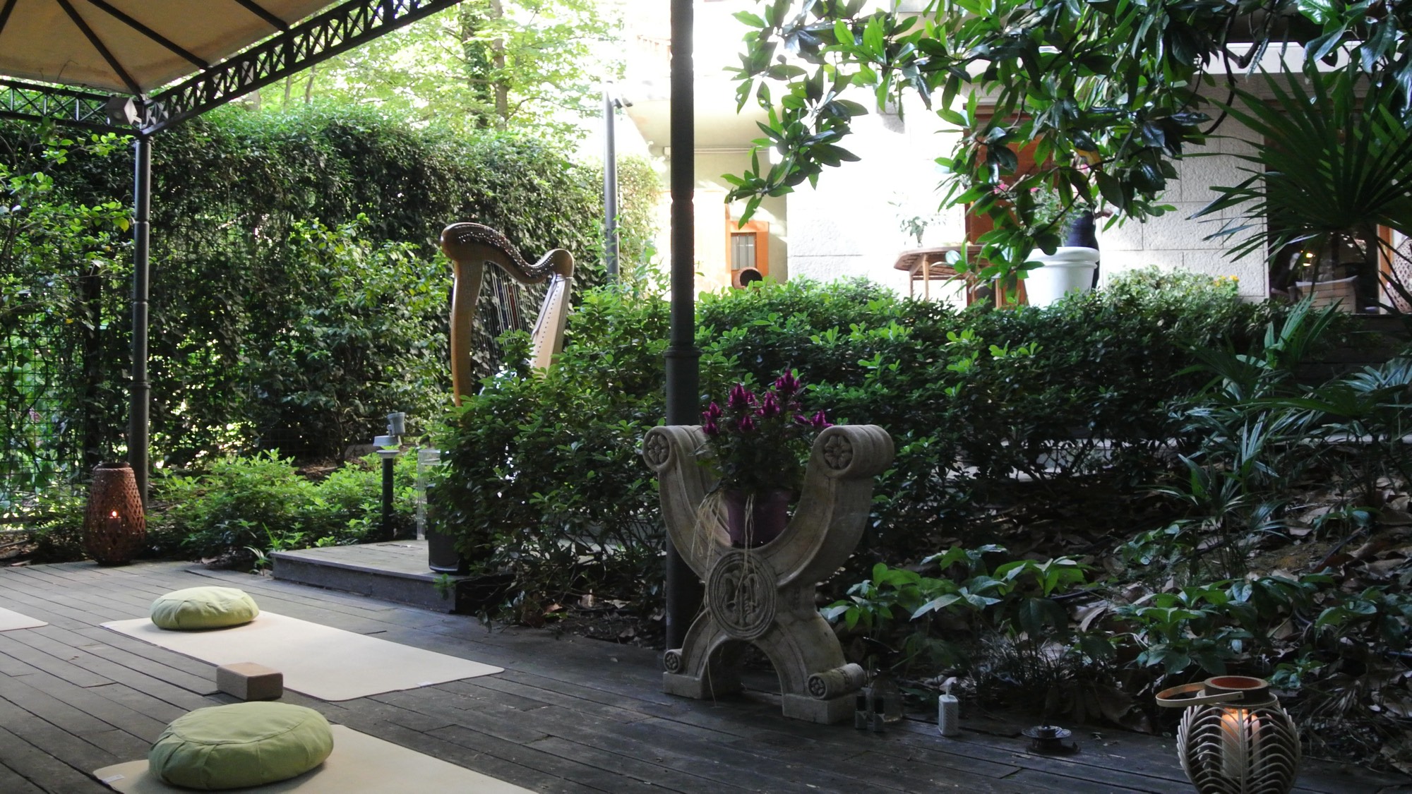 A harp and lanterns set in a lush Milan garden, mats ready for the sunset practice